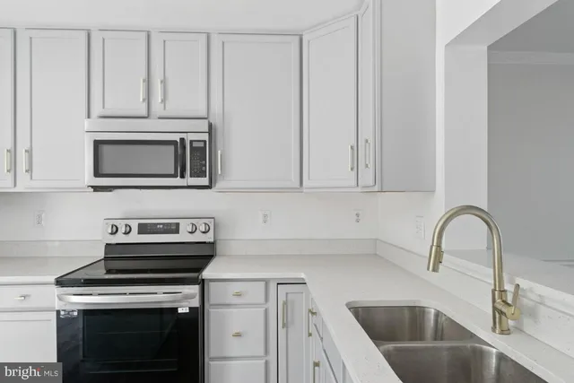 a kitchen with granite countertop white cabinets and stainless steel appliances