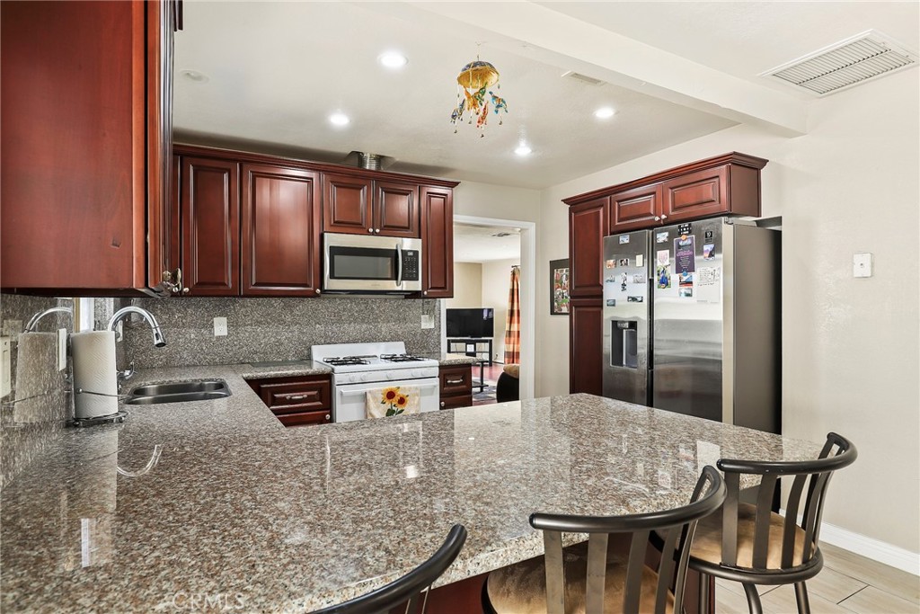 19709 Strathern Street Winnetka, CA 91306 - Photo 13 of 31 a kitchen with stainless steel appliances granite countertop a stove refrigerator sink and cabinets