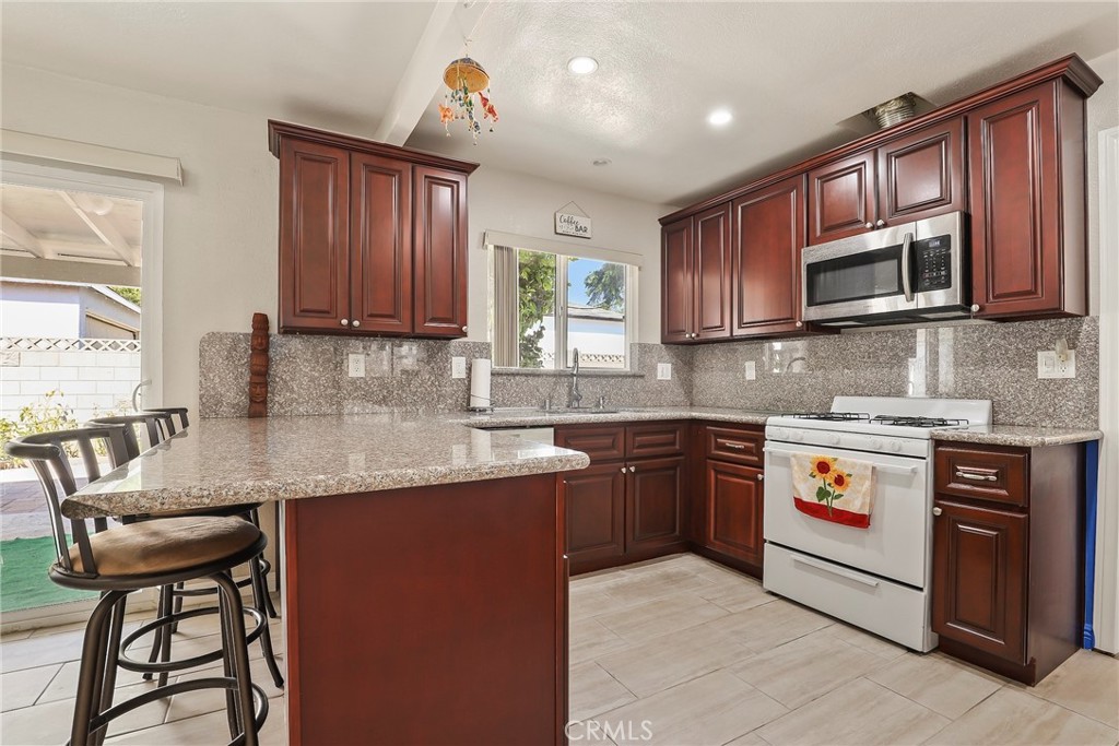 19709 Strathern Street Winnetka, CA 91306 - Photo 9 of 31 a kitchen with stainless steel appliances granite countertop a stove sink microwave and cabinets