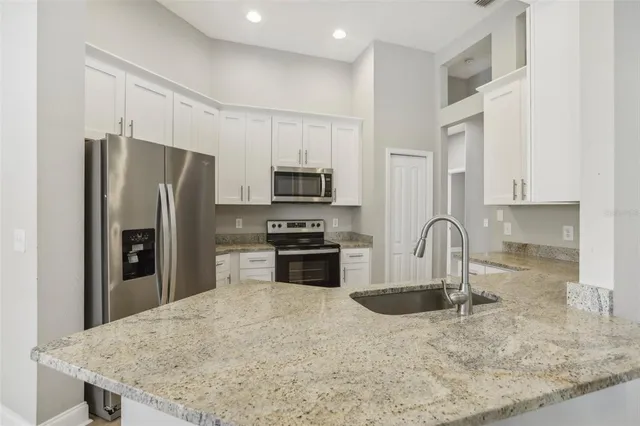 a kitchen with granite countertop a refrigerator and a sink