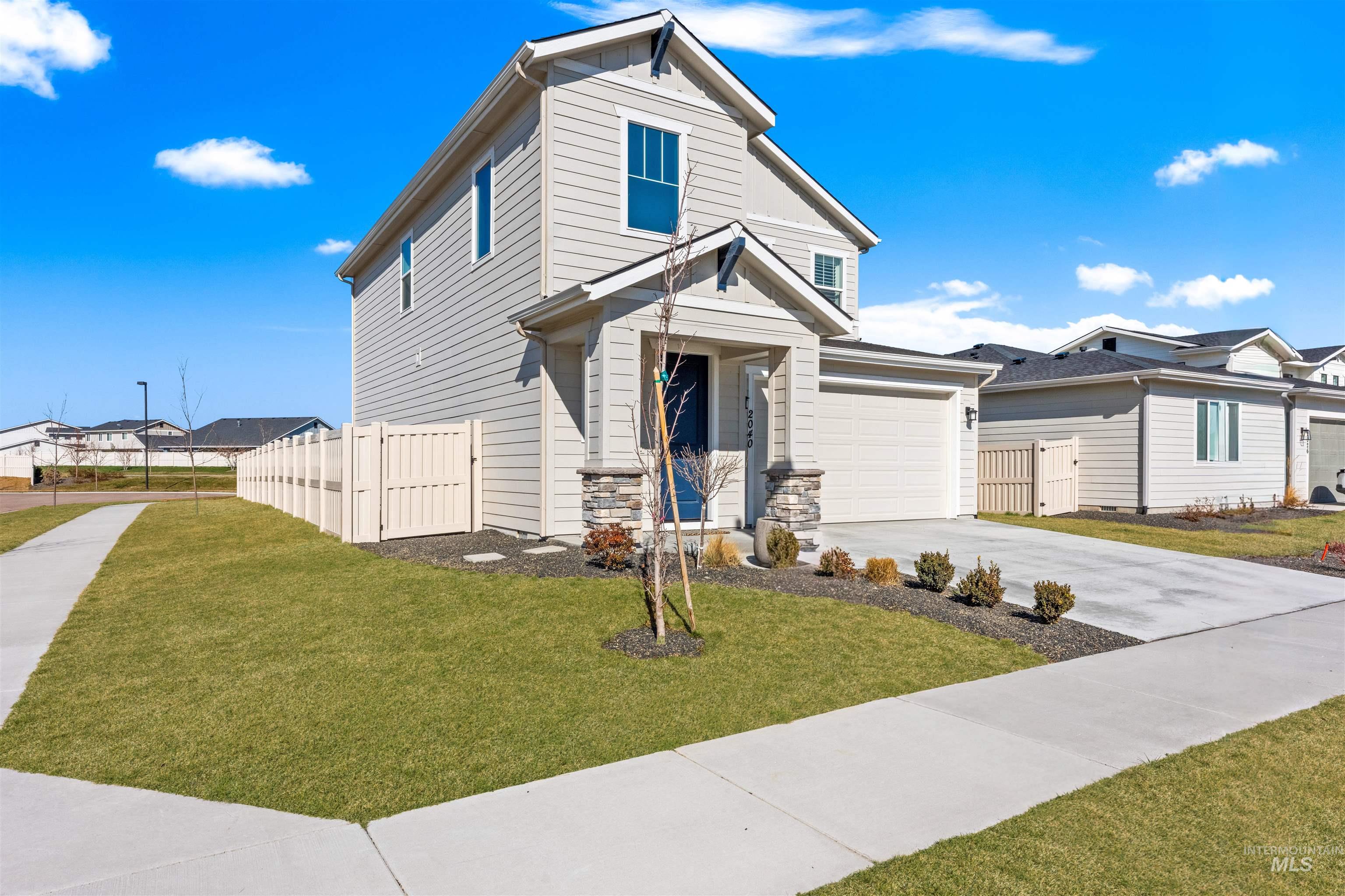 View of front facade featuring concrete driveway, stone siding, and a gate