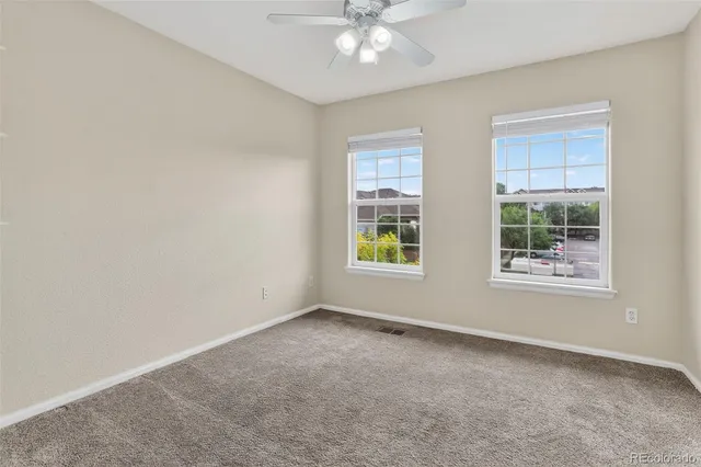 an empty room with windows and chandelier fan