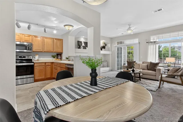 a living room with stainless steel appliances furniture a rug and a kitchen