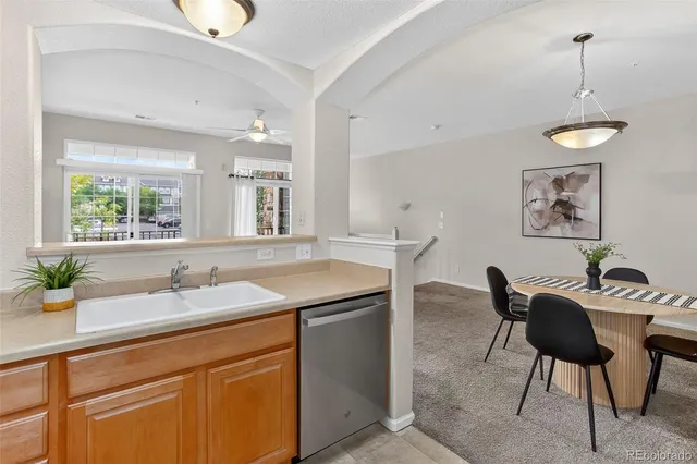 a kitchen with stainless steel appliances granite countertop a sink a stove a dining table and chairs with wooden floor