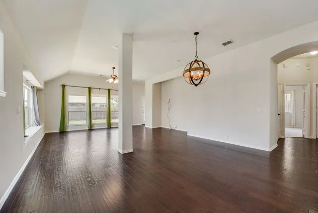 a hallway with wooden floor chandelier and entryway