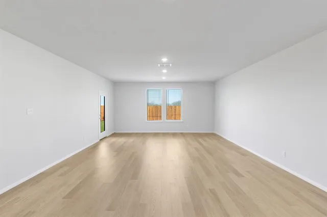 a view of a big room with wooden floor and windows