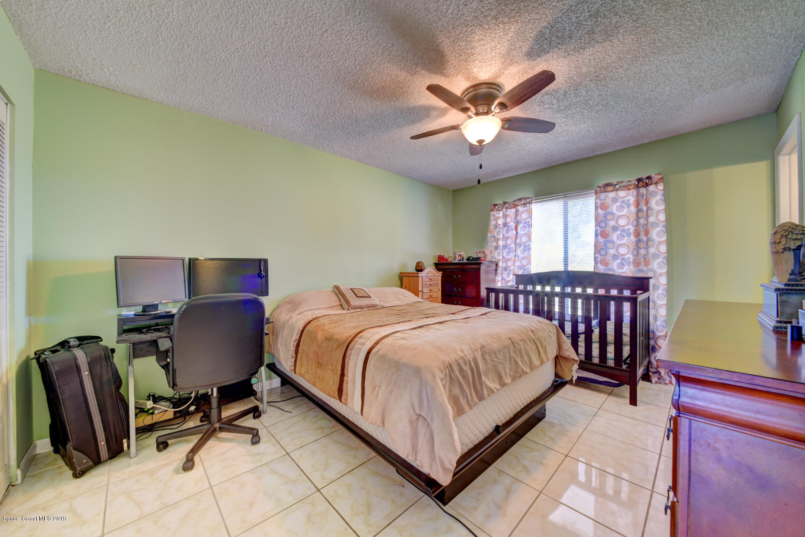 1300 Cromey Road Northeast Palm Bay, FL 32905 - Photo 17 of 29 a bedroom with a bed chair and a window