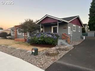 a view of a house with a small yard and large tree
