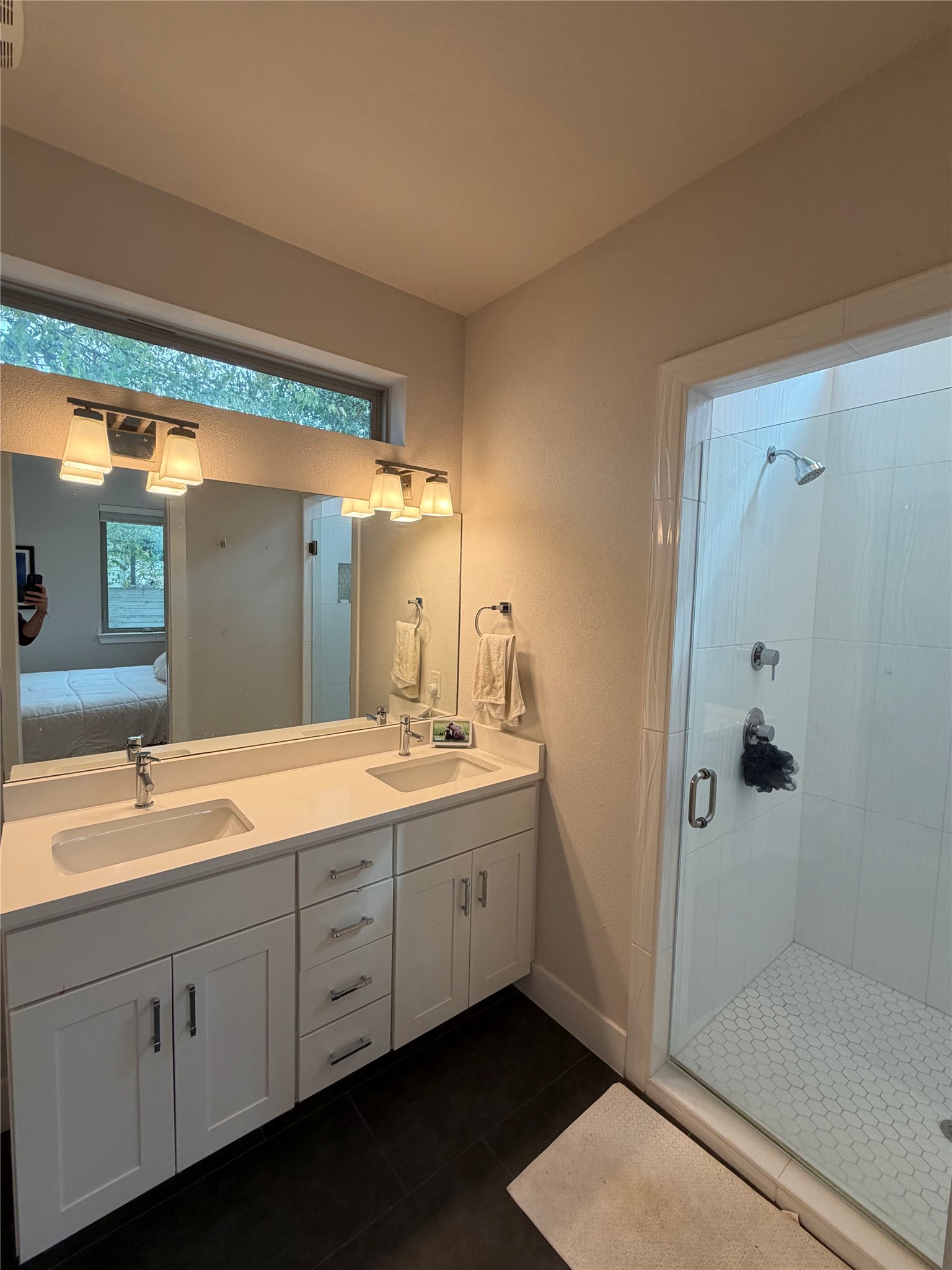 1159 Webberville Road, Unit A Austin, TX 78721 - Photo 17 of 26 Bathroom featuring ensuite bathroom, double vanity, a stall shower, and dark tile patterned flooring