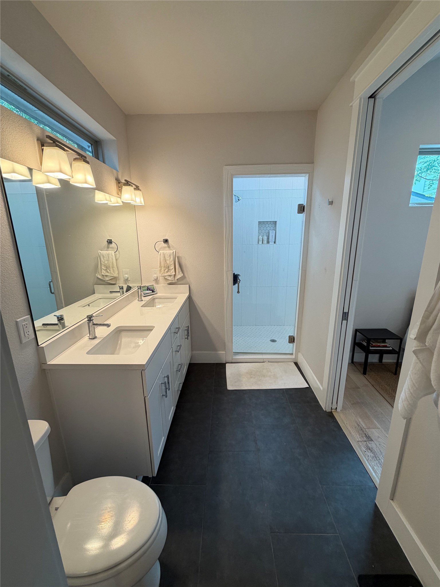 1159 Webberville Road, Unit A Austin, TX 78721 - Photo 18 of 26 Bathroom with double vanity, a stall shower, and dark tile patterned floors