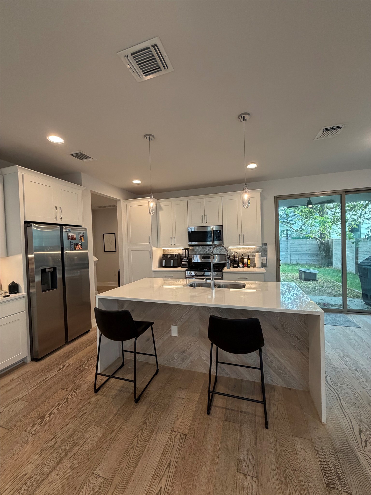 1159 Webberville Road, Unit A Austin, TX 78721 - Photo 8 of 26 Kitchen with pendant lighting, appliances with stainless steel finishes, a kitchen bar, an island with sink, and recessed lighting