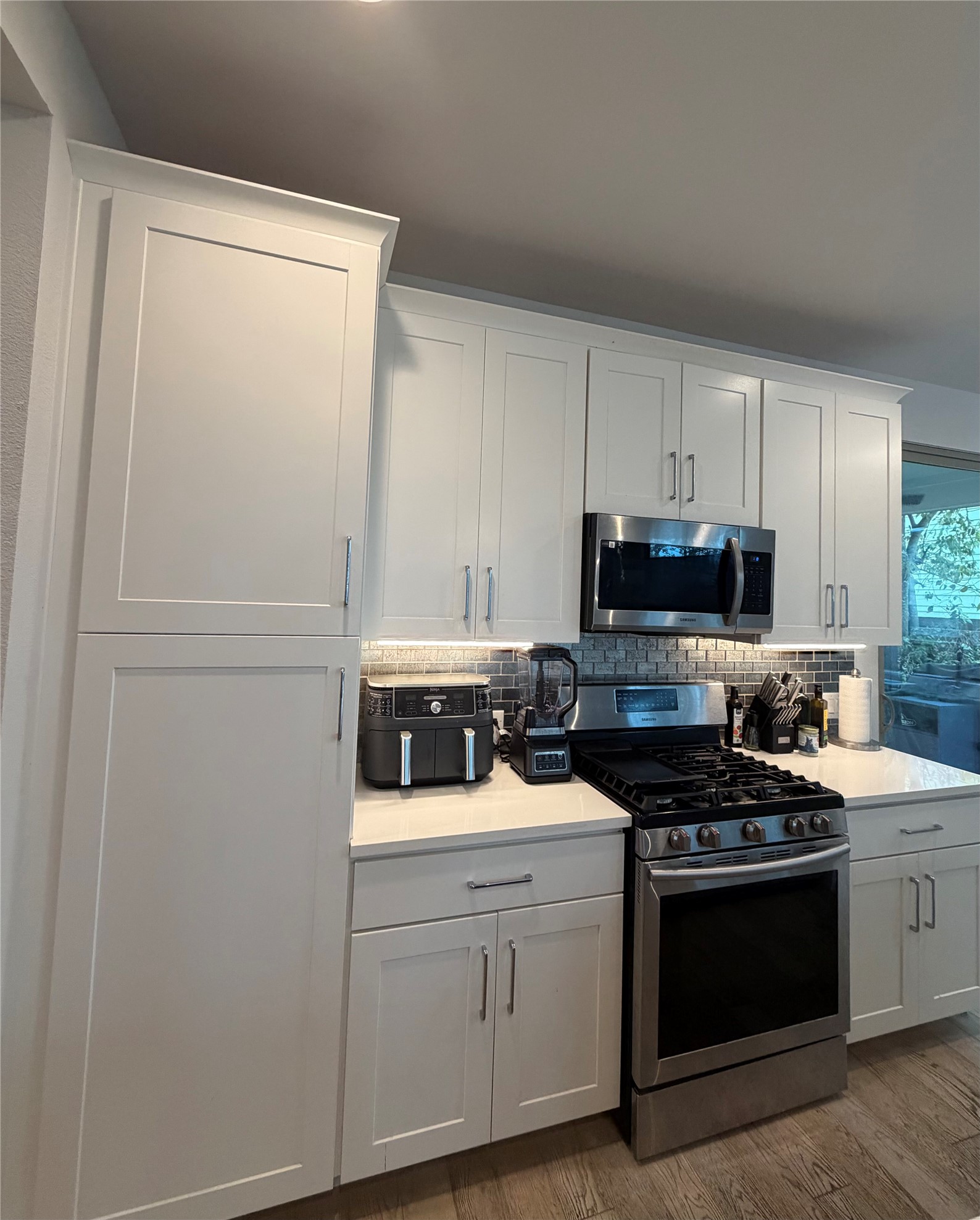 1159 Webberville Road, Unit A Austin, TX 78721 - Photo 10 of 26 Kitchen with stainless steel appliances, white cabinets, backsplash, and dark wood-style flooring