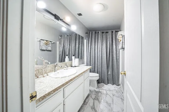 a bathroom with a granite countertop sink a toilet and a mirror