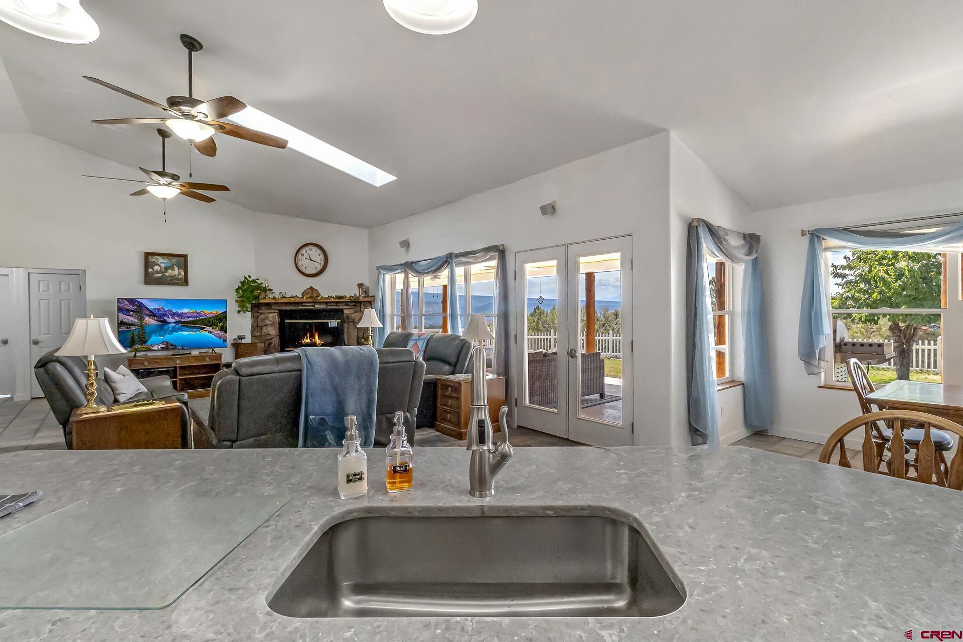 17656 2550th Road Cedaredge, CO 81413 - Photo 11 of 45 a kitchen with stainless steel appliances a sink a faucet a chandelier and a view of living room