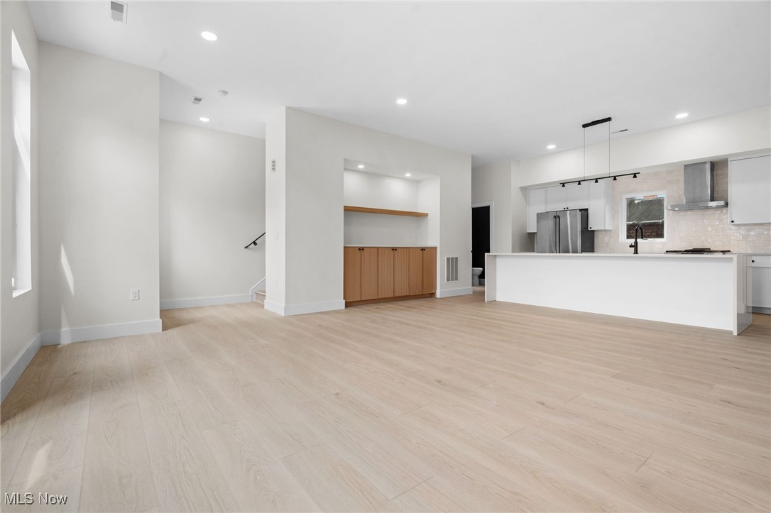 Unfurnished living room featuring recessed lighting, light wood-style floors, and stairway
