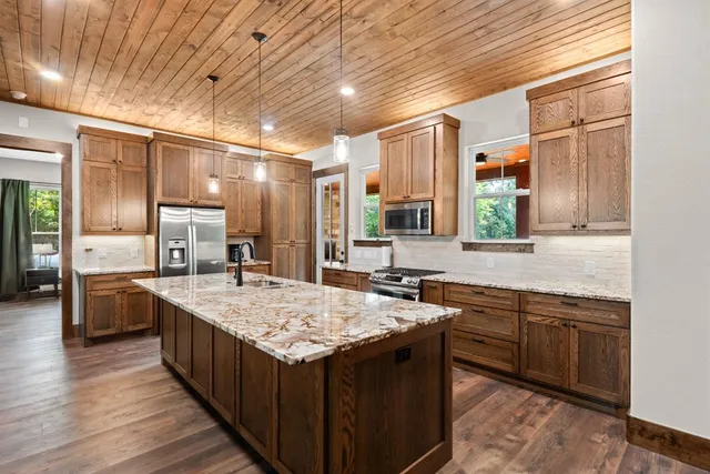 a large kitchen with kitchen island a sink stove and wooden cabinets