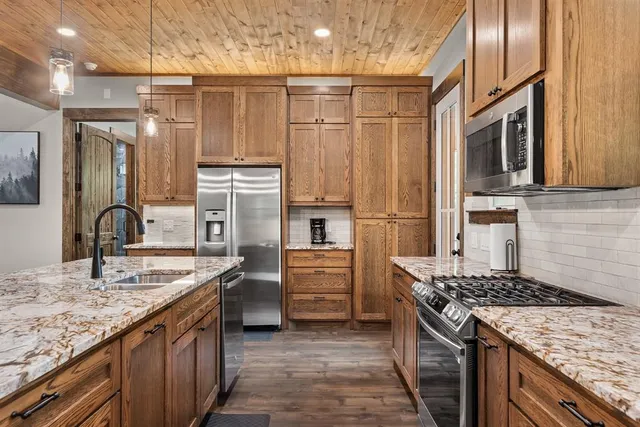 a kitchen with kitchen island granite countertop a sink stove and refrigerator