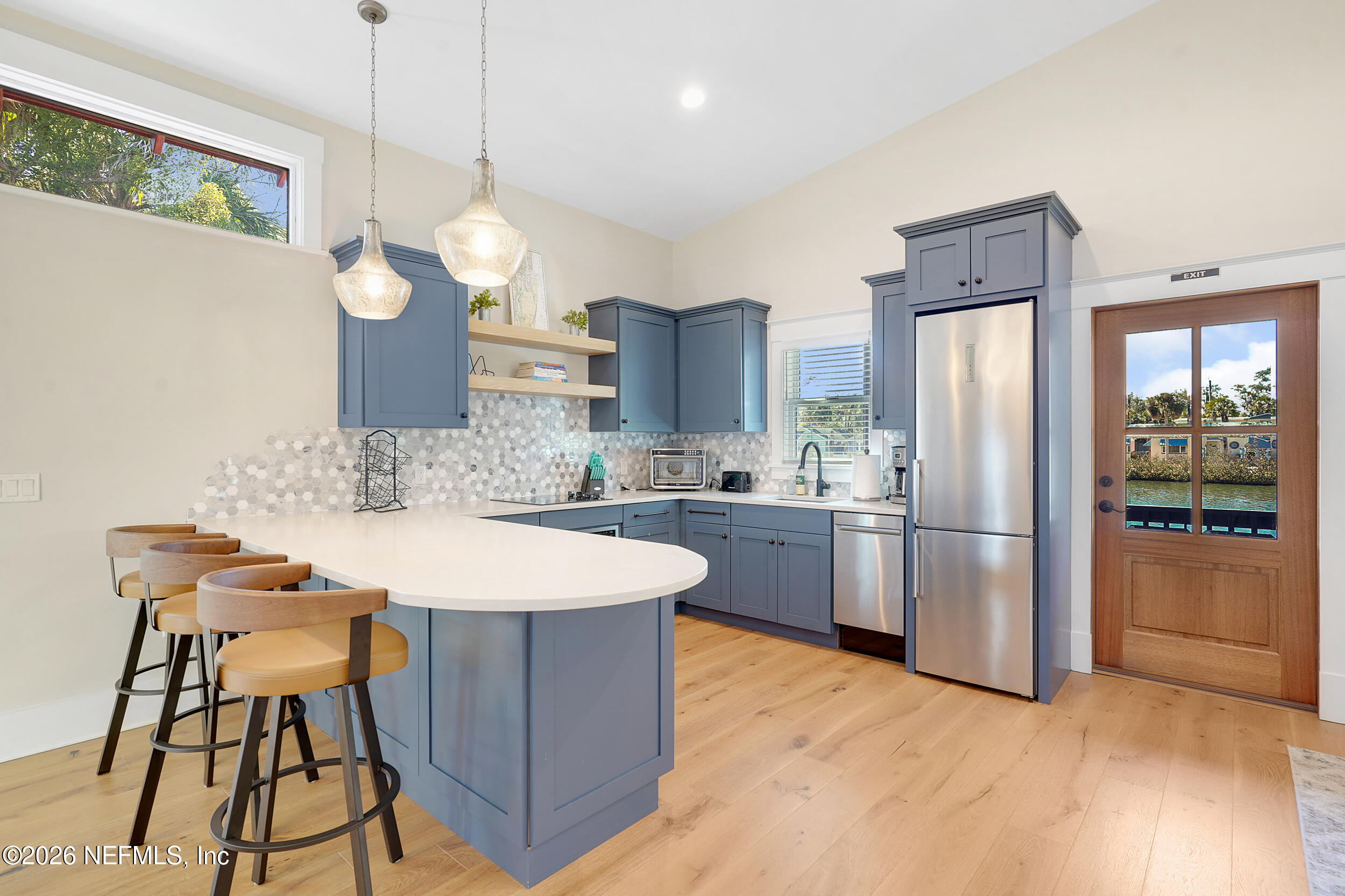 290 St George Street, Unit B St. Augustine, FL 32084 - Photo 8 of 19 a large kitchen with stainless steel appliances kitchen island granite countertop a refrigerator a stove a sink and a dining table with wooden floor