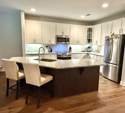 a kitchen with stainless steel appliances granite countertop a stove a sink a microwave a dining table and chairs