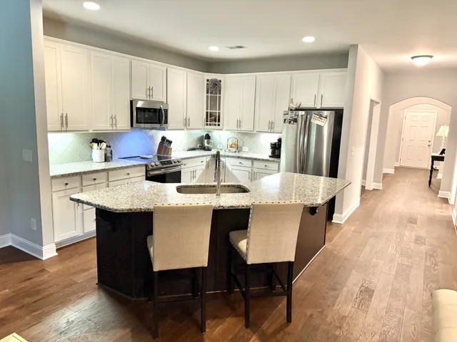 a kitchen with stainless steel appliances a dining table chairs microwave and sink