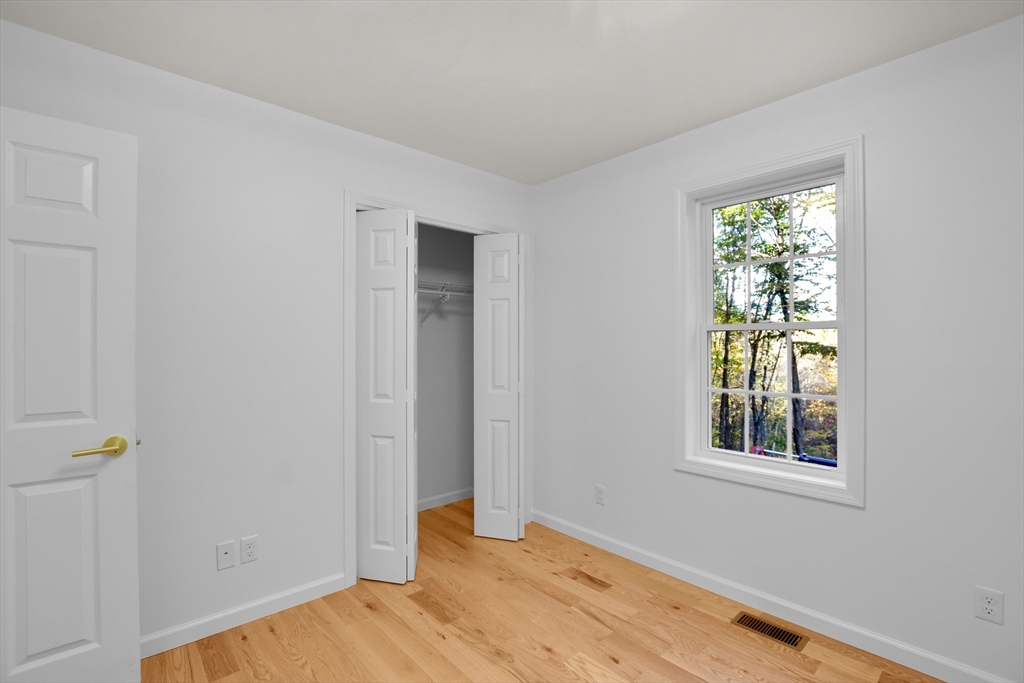 76 Number 6 Schoolhouse Road Charlton, MA 01507 - Photo 8 of 29 a view of an empty room with wooden floor and a window