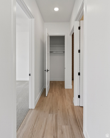 2862 South Mountain Rnch Road Cedar City, UT 84720 - Photo 33 of 64 Hallway featuring wood-finish flooring, recessed ceiling lighting, a closet with wire shelving and hanging rod, white walls, and dark hardware