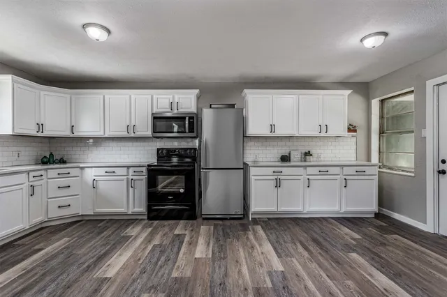 a kitchen with granite countertop white cabinets and refrigerator