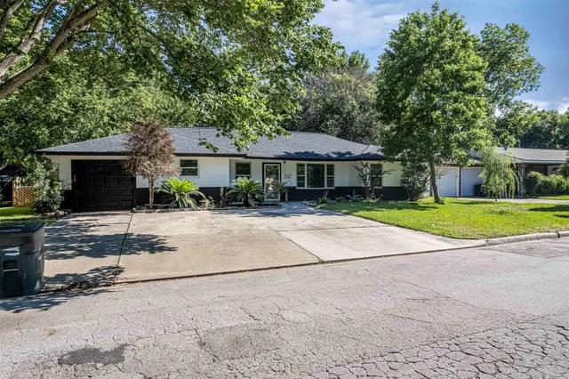 a view of a house with a yard and large tree