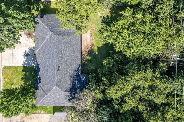 an aerial view of a house with a yard and large trees