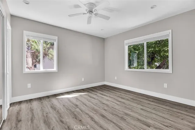 an empty room with wooden floor and windows