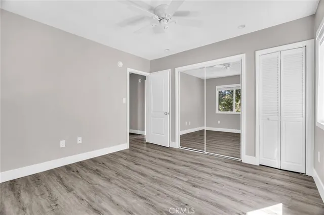 a view of an empty room with wooden floor & entryway