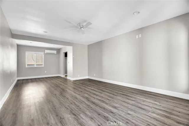 a view of an empty room with wooden floor and window