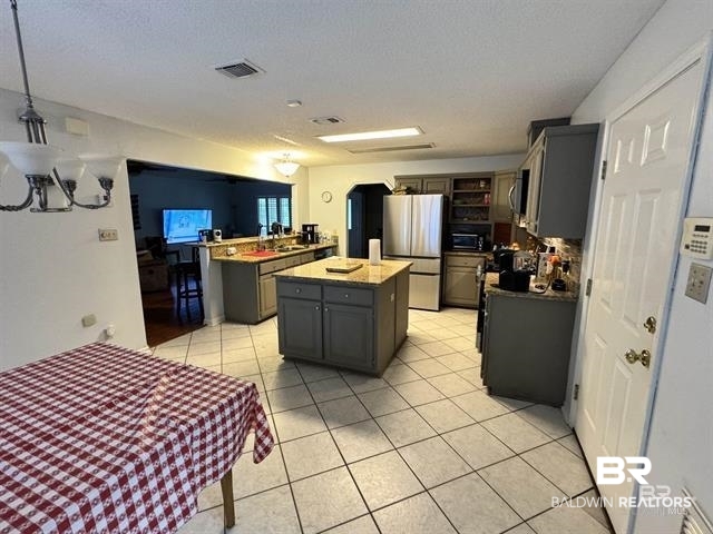 23393 Miflin Road Foley, AL 36535 - Photo 6 of 12 Kitchen featuring visible vents, gray cabinets, freestanding refrigerator, and a center island