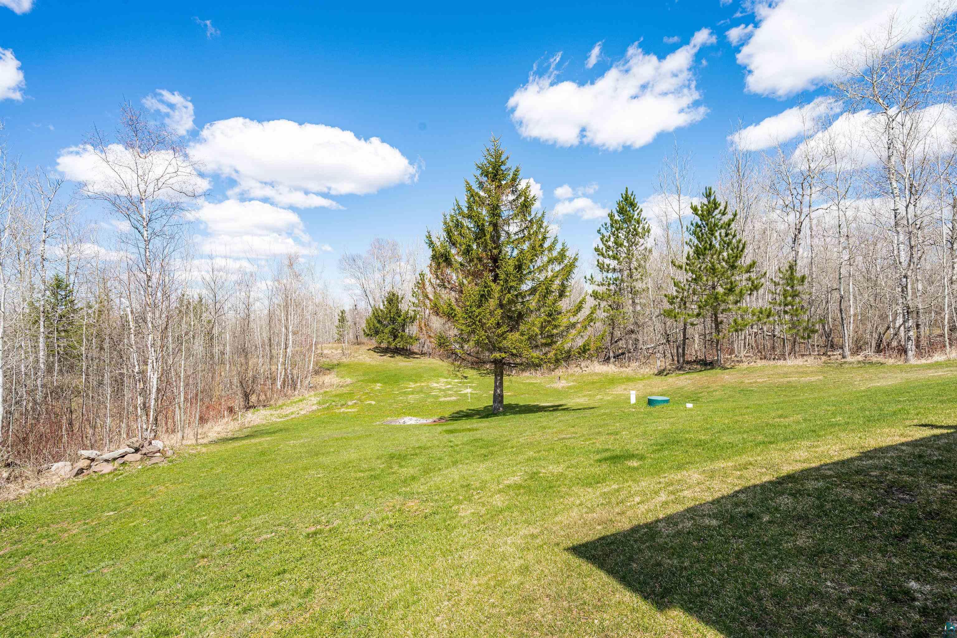 3325 Strand Road Duluth, MN 55803 - Photo 8 of 25 Expansive green lawn surrounded by mature trees, featuring a prominent foreground.