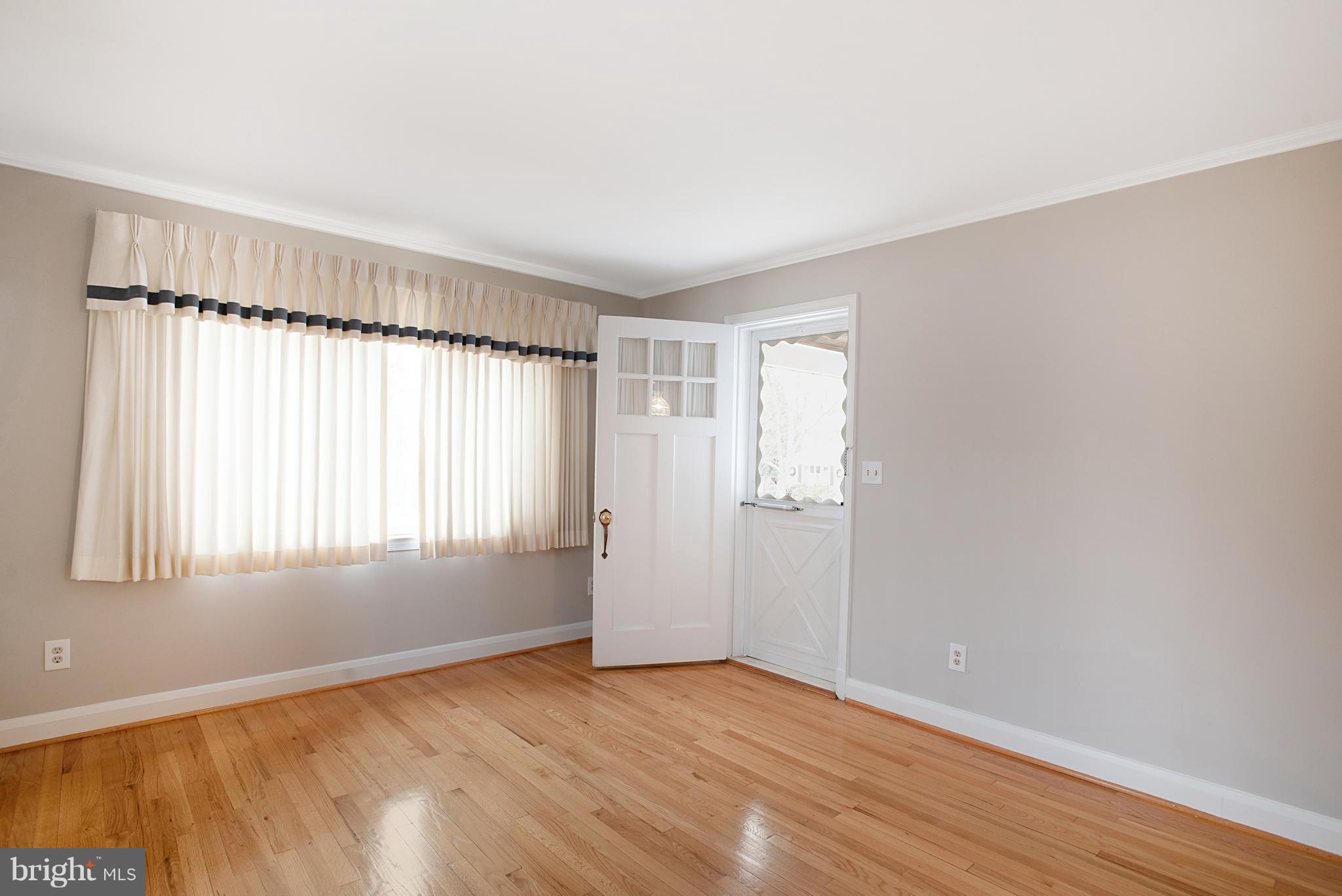 3300 Garnet Road Baltimore, MD 21234 - Photo 12 of 55 an empty room with wooden floor and windows with curtains