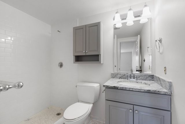 a bathroom with a granite countertop toilet sink and mirror