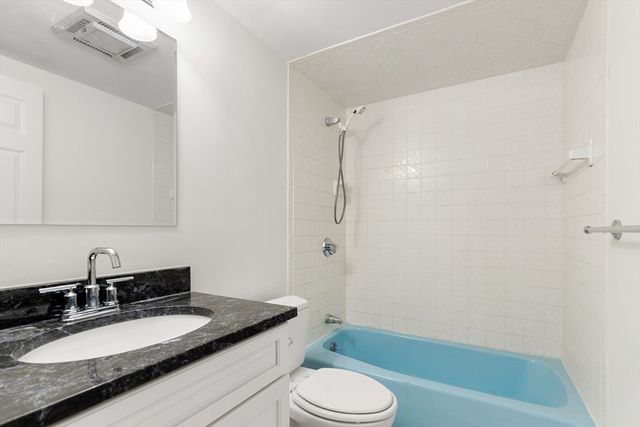 a bathroom with a granite countertop sink toilet mirror vanity and shower