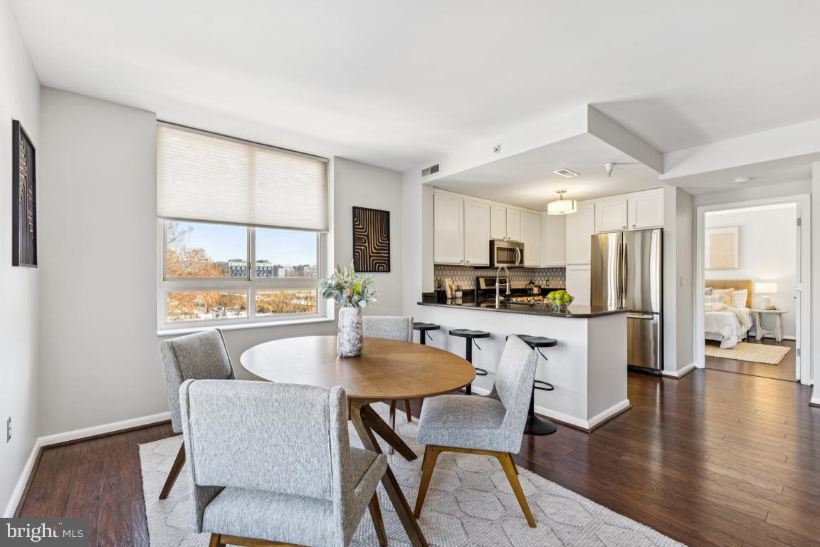355 I Street Southwest, Unit 501 Washington, DC 20024 - Photo 7 of 44 a kitchen with stainless steel appliances granite countertop a stove a refrigerator a kitchen island a dining table and chairs with wooden floor