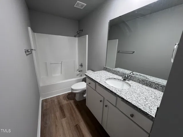 a bathroom with a granite countertop sink a toilet and shower