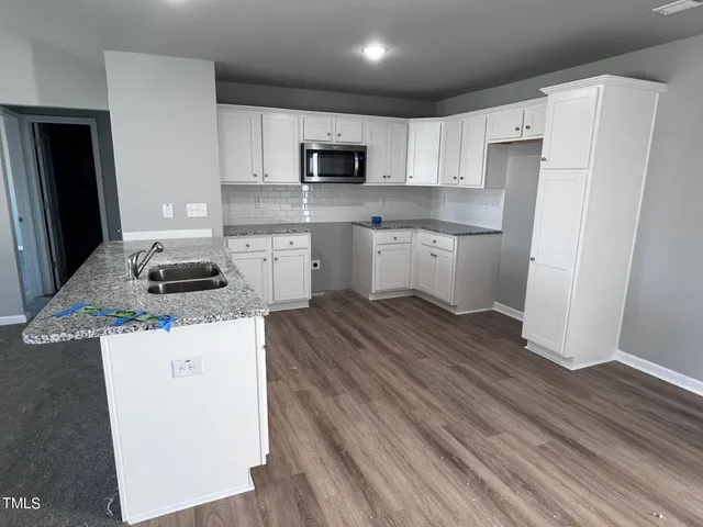 a kitchen with granite countertop a refrigerator stove top oven and sink