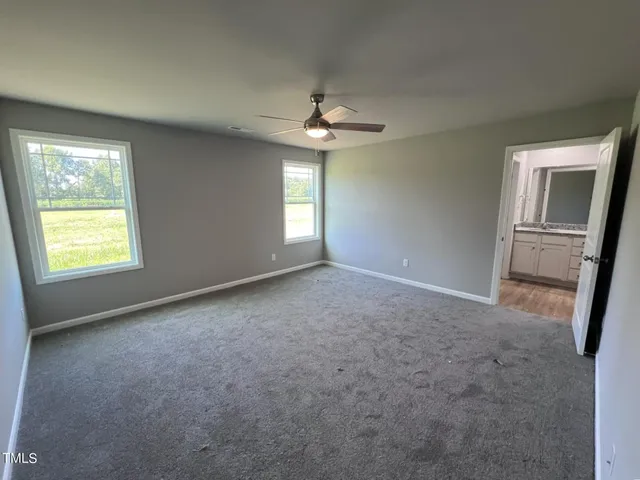 an empty room with windows and fan