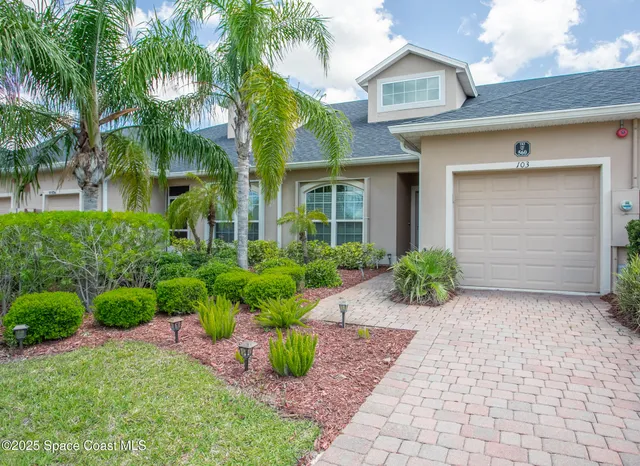 a front view of a house with a yard and potted plants