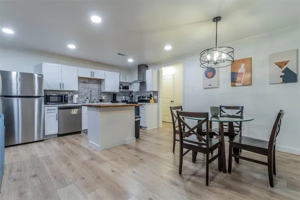 a kitchen with stainless steel appliances granite countertop a dining table chairs refrigerator and microwave