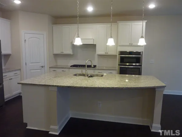 a kitchen with kitchen island granite countertop a sink a stove and cabinets