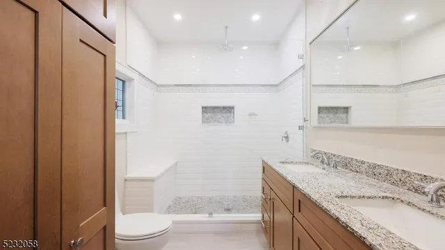 a bathroom with a granite countertop sink a toilet a mirror and shower