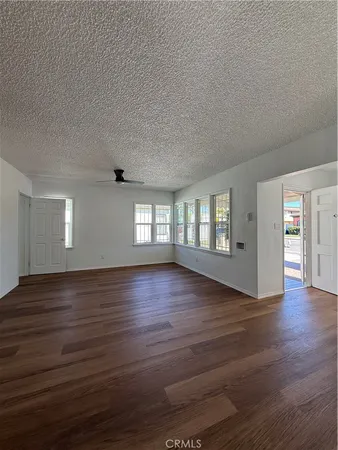 a view of an empty room with wooden floor and window