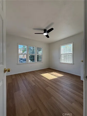 a view of empty room with wooden floor and fan