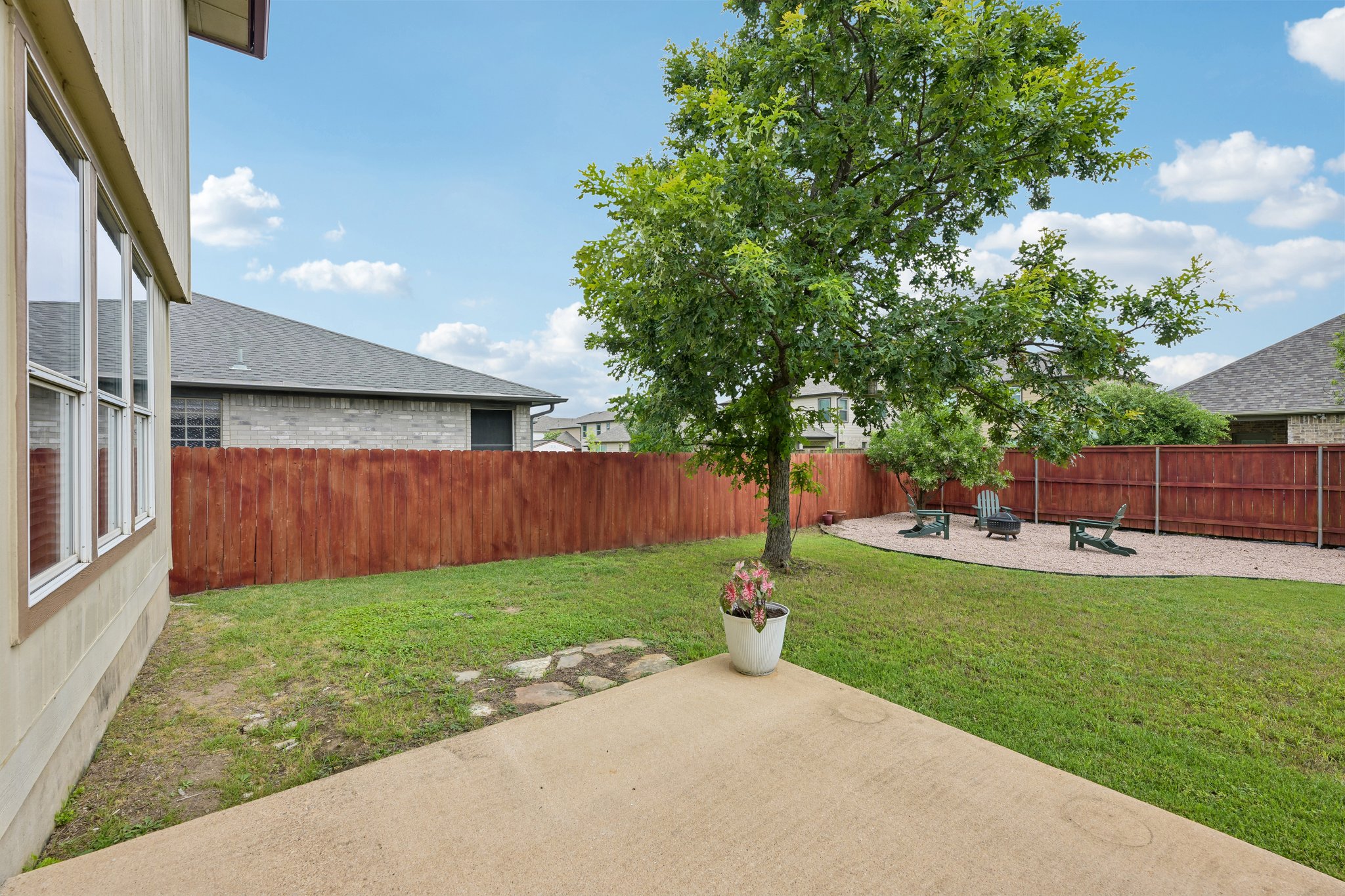 4100 Mocha Trail Austin, TX 78728 - Photo 3 of 33 A fenced backyard offers a concrete patio and a gravel seating area under mature trees.