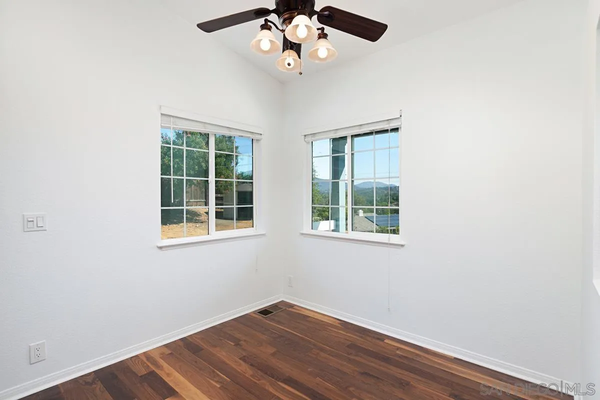 1064 Ranchito Vista Alpine, CA 91901 - Photo 16 of 31 an empty room with wooden floor chandelier fan and windows