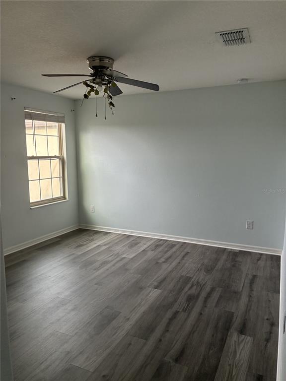 9616 Lemon Drop Loop Sun City Center, FL 33573 - Photo 34 of 53 an empty room with wooden floor fan and windows